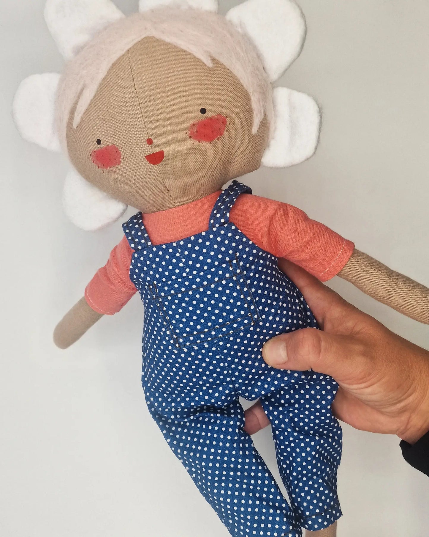 Handmade Daisy doll wearing blue polka dot dungarees and an orange shirt, with a cheerful hand-painted face and petal-shaped hair