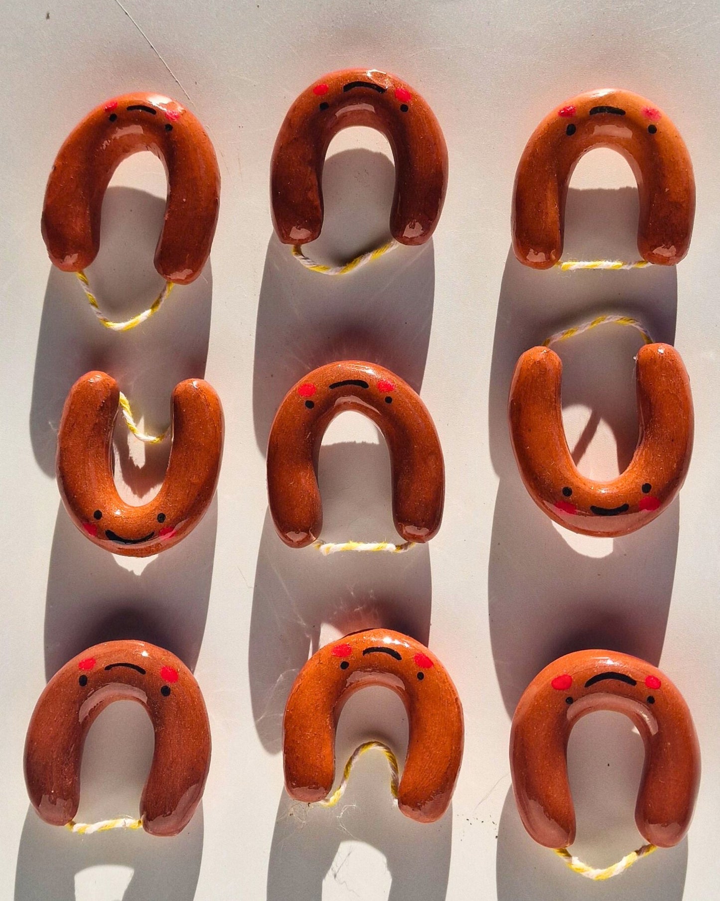 Group of handmade ceramic Alheirita brooches/magnets with different facial expressions, arranged on a white background